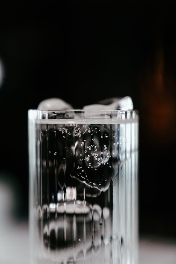 Close-up of a refreshing soda with ice cubes in a glass on a dark background.